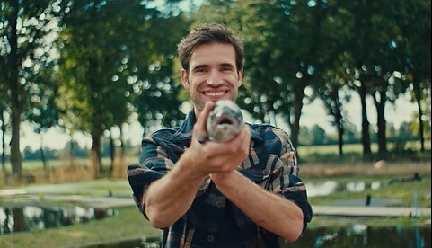 Lachende man houdt een zalm vast in de leefomgeving van de zalm op zalmboerderij Maashorst.