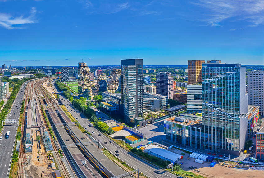 Luchtfoto van zakendistrict Amsterdam Zuidas met moderne kantoorgebouwen naast het spoor.
