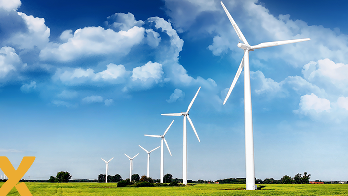 Rij van moderne windturbines in een groen landschap onder een heldere blauwe lucht.