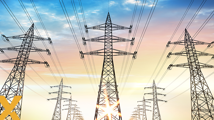 Rij hoogspanningsmasten met elektriciteitskabels bij zonsopkomst of zonsondergang.