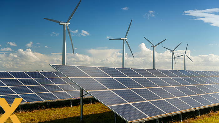 Zonnepanelen op een veld met windmolens op de achtergrond onder een heldere blauwe lucht